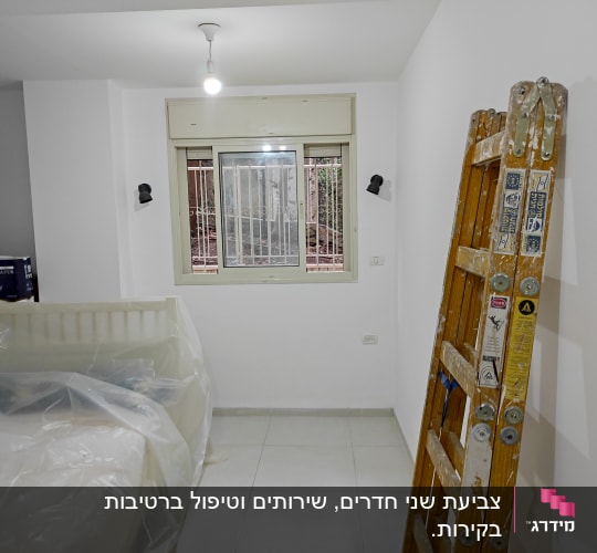 סולם עץ עם כתמי צבע בחדר צבוע לבן